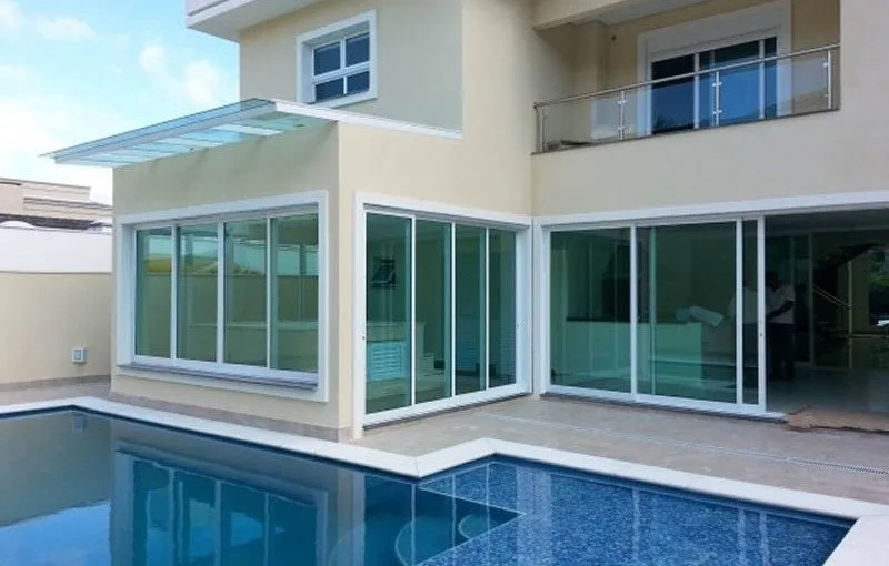 Sobrado com portas e janelas de vidro temperado voltadas para a piscina